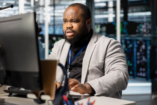Worried server hub IT expert unnerved by infrastructure failure errors found during analysis. African american programmer in data center disturbed after detecting unexpected network outage photo