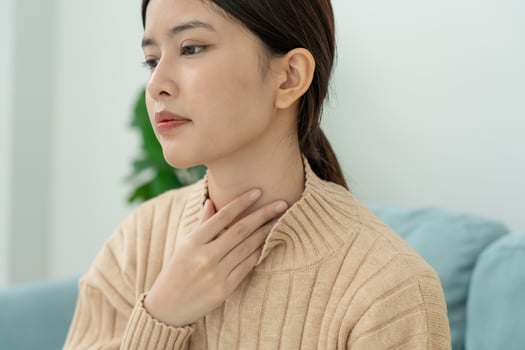 Asian woman put on neck due to a sore throat. female tonsillitis causes a inflammation. treated by taking water, taking antibiotics, consult a doctor, virus, corona virus. photo