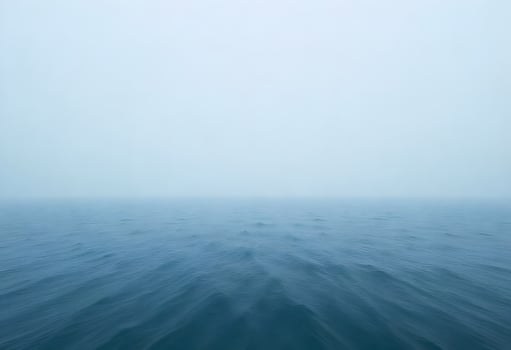 Tranquil Ocean Vista with Soft Ripples Under a Hazy Sky in Muted Blue and White photo