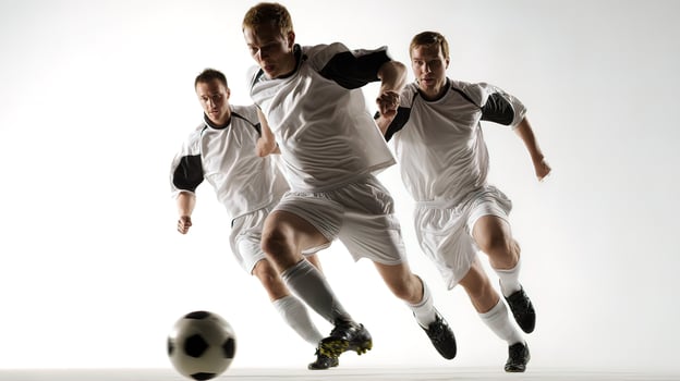 Three men in white soccer uniforms are running after a soccer ball photo
