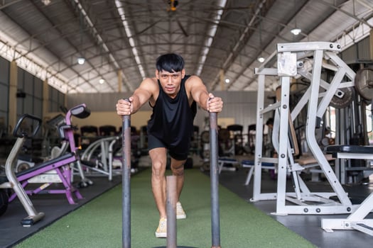 Pushing Limits. Young Man Training with Weighted Sled at Gym photo
