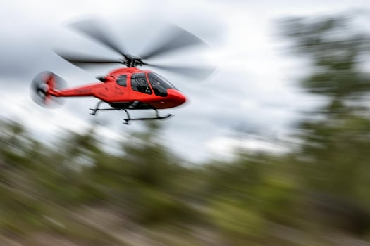 A red helicopter flying through the air photo