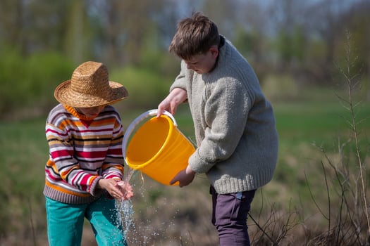 Two boys wash their hands by pouring water from a bucket photo