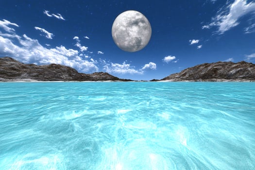 A full moon over the ocean with a blue sky photo
