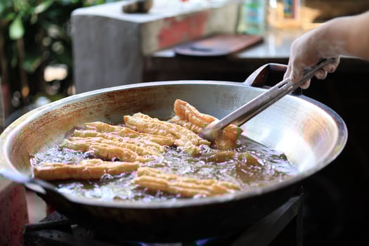 Man Hand Fried Chinese Deep Fried Dough Stick or Youtiao in Big Pan photo