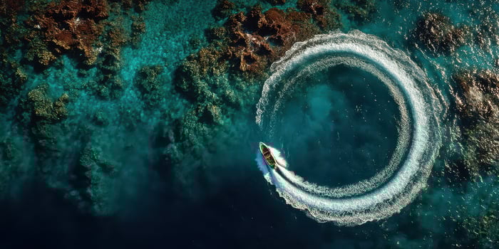 Boater makes a perfect circle in a clear blue lagoon surrounded by coral reefs during a sunny day photo