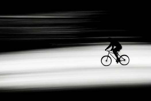 A person riding a bike in a black and white photo