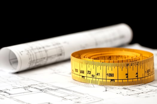 A yellow tape measure is sitting on top of a blueprint photo