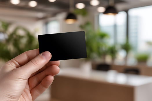 Hand holding blank black business card in modern office photo