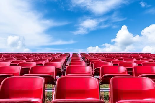Red seats in a stadium with a blue sky photo