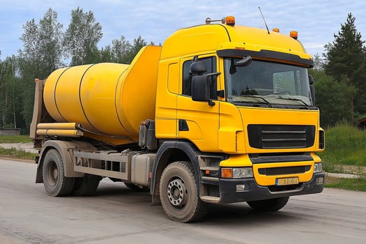 A yellow truck driving down a road photo