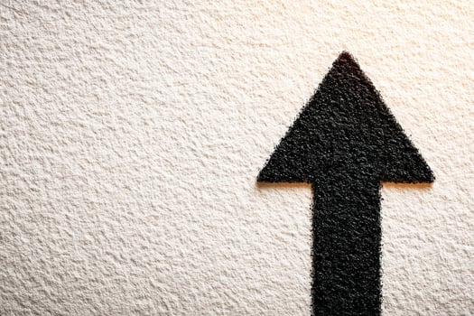 A bold black arrow is displayed prominently on a textured white surface, emphasizing direction and movement. The stark contrast creates a striking visual impact. photo