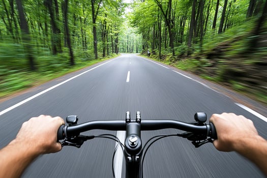 A person riding a bicycle down a road in the woods photo