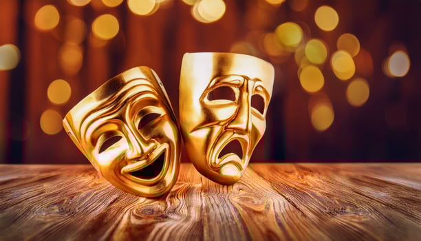 A pair of golden comedy and tragedy masks lying on a wooden stage, reflecting the essence of theatrical emotion. photo
