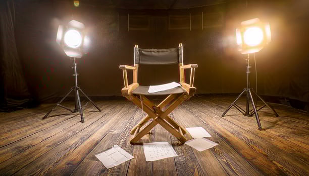 Empty directors chair on a wooden floor, surrounded by scattered script pages and illuminated by two bright spotlights. Dark background. photo