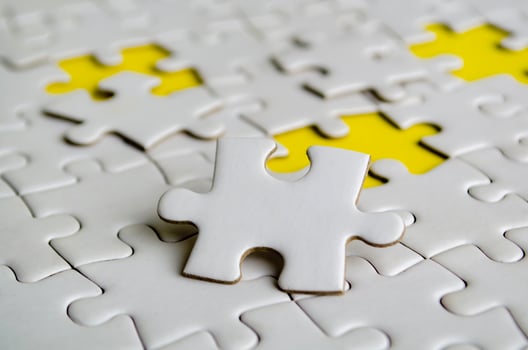 Close up of white jigsaw puzzle pieces placed on a bright yellow background with customizable space on jigsaw for text or ideas. photo