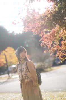 Cheerful Asian woman in casual dress enjoys autumn foliage, smiling under vibrant maple tree, embracing Japanese tradition outdoors photo