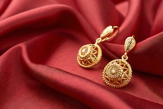 golden earrings on red silk fabric photo