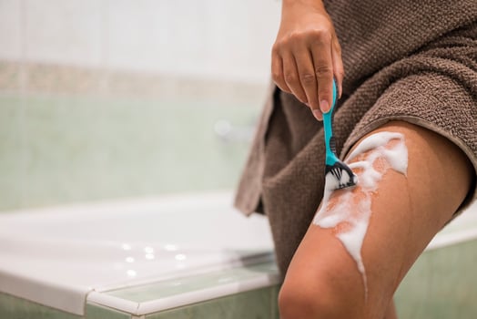 a girl holds a razor in her hands for epilation and hair removal on the body and legs in the bathroom photo
