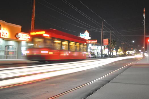 A red bus driving down a street at night photo