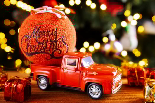 Red toy truck with Christmas balloon and gift boxes on wooden table photo