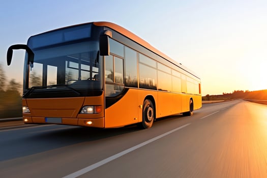 A bus driving down the road at sunset photo