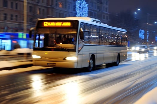 A bus driving down a snowy street at night photo