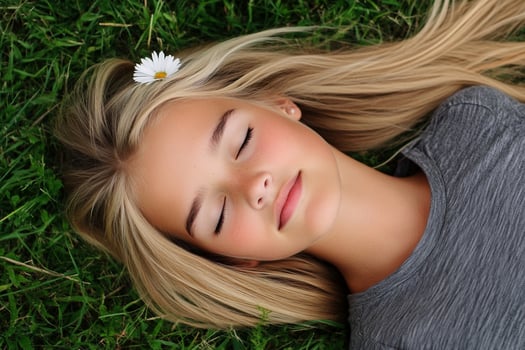 A young girl laying on the grass with her eyes closed photo