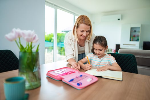 A mother helps her daughter with homework at the table photo