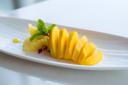 Artistic arrangement of mango and pineapple slices on white plate for summer refreshment photo