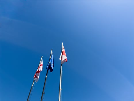 Tbilisi, Georgia, 09 May 2025. Flags of Georgia and Europe against a blue sky, copy space photo