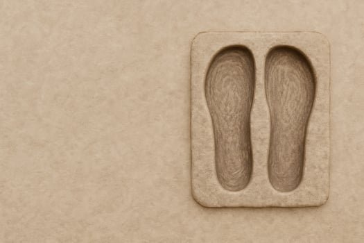 An artistic and minimalist composition reveals a textured, earth-toned foot impression on a rectangular tablet. photo