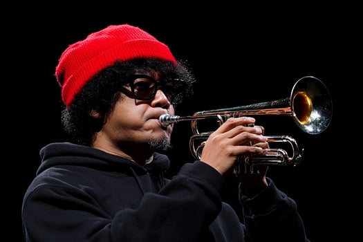 A man in a red hat plays a trumpet photo
