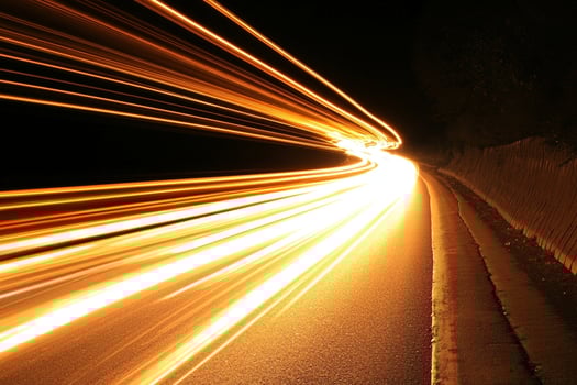 A long exposure of a car driving on a road at night photo