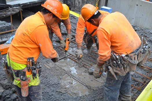 Construction workers in orange shirts working on concrete photo