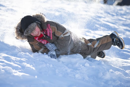 Happy little boy is rolling down a snow slide. Child in winter. photo