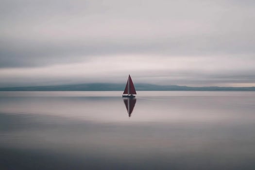 A sailboat floating in the water on a cloudy day photo