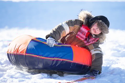 Happy little boy sledding on a snow slide. Child in winter photo