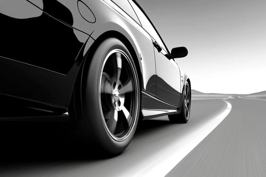 Black and white image of a car driving down the road photo
