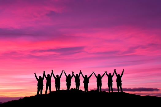 Silhouette of people standing on top of a hill with their hands up photo