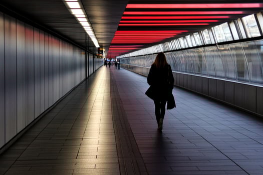 A woman walking down a long hallway with red lights photo