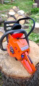 Chainsaw and headphones on a freshly cut block of wood photo