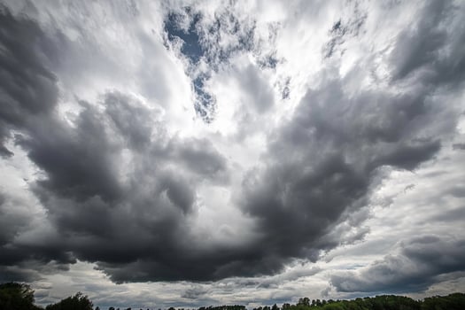 A large cloud is seen in the sky above a field photo