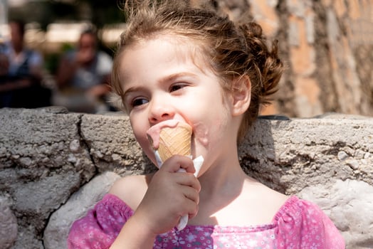 Cute girl in pink dress eating ice cream photo