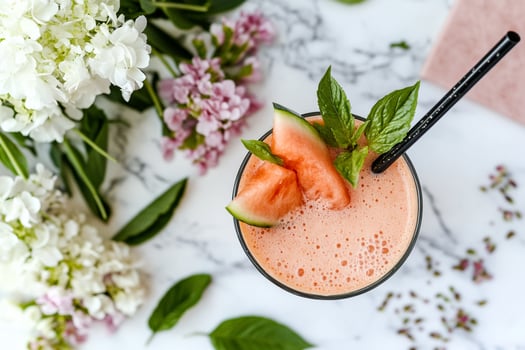 A glass of watermelon smoothie with a black straw photo