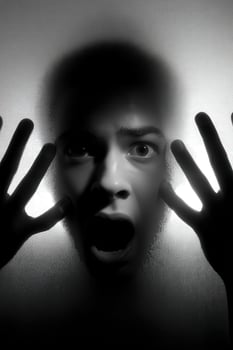 Person expresses fear while pressed against a fogged glass surface photo