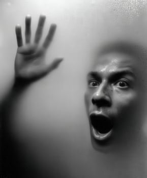 Person behind fogged glass looking surprised and frightened photo