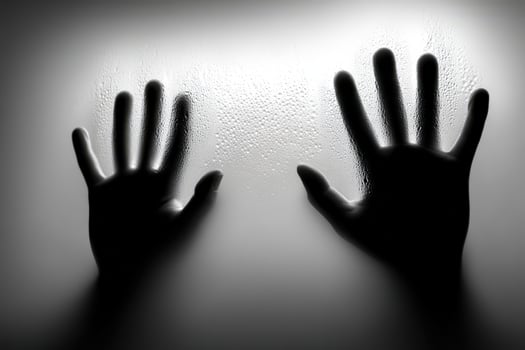 Hands pressing against a fogged window in black and white photo