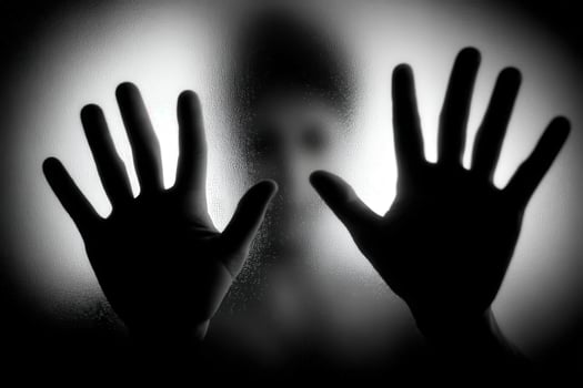 Hands pressed against a foggy surface with a silhouette behind photo