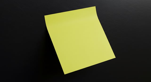 A yellow sticky note is hanging on a black surface photo